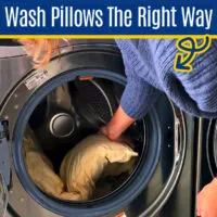 Image of someone washing pillows in a washing machine for a post about how to wash pillows in a washing machine.