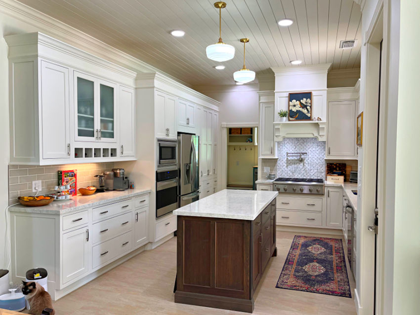 White kitchen cabinets in a 10' high ceiling kitchen with an island and shiplap kitchen ceiling.
