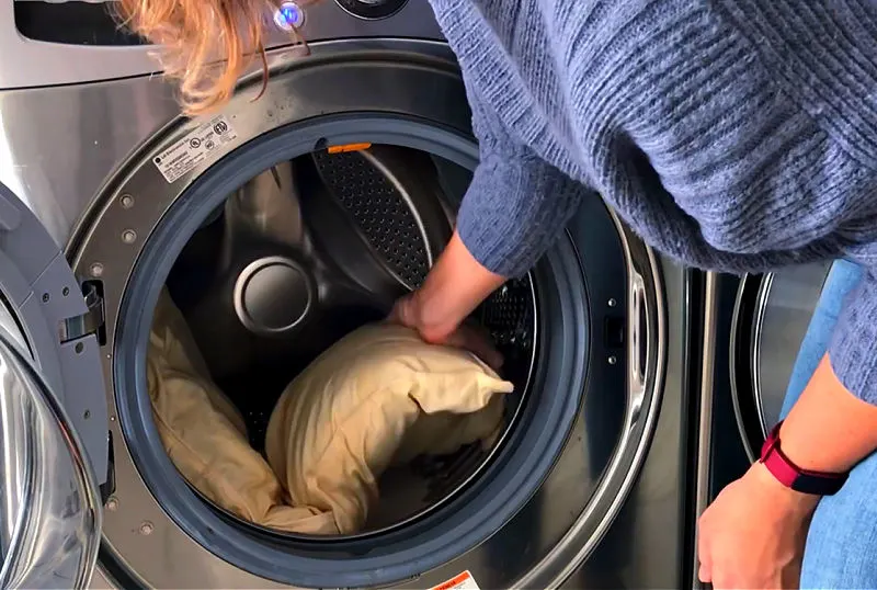 Image shows someone cleaning a pillow in a washing machine.