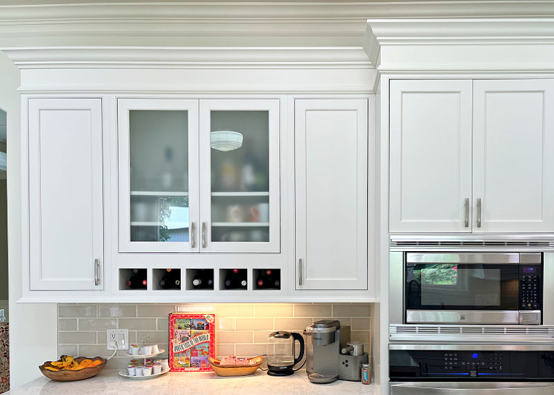 Drink bar area in a white kitchen with trim and crown molding.