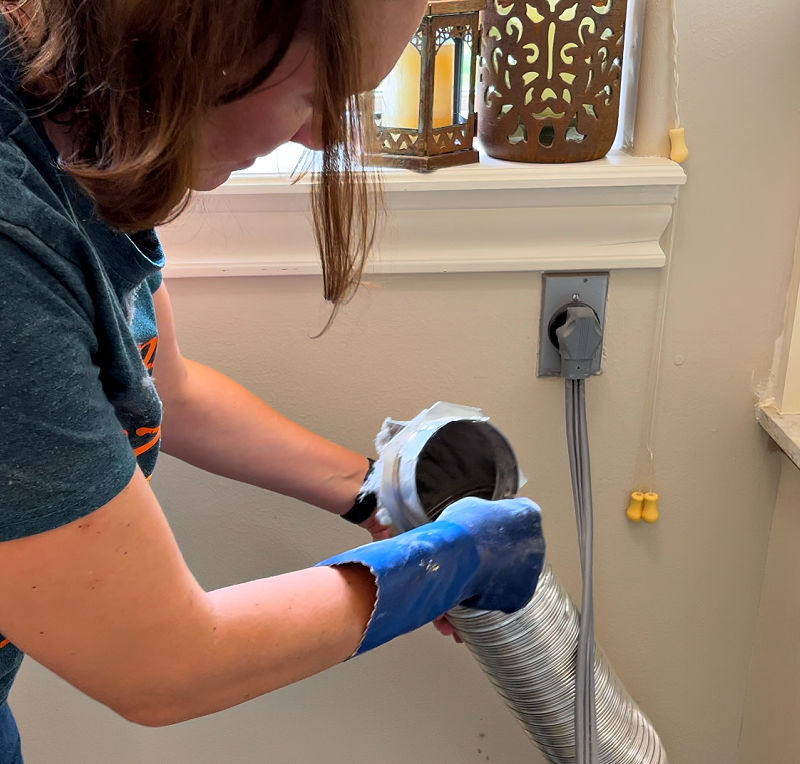 Inspecting a dryer duct for lint and damage.