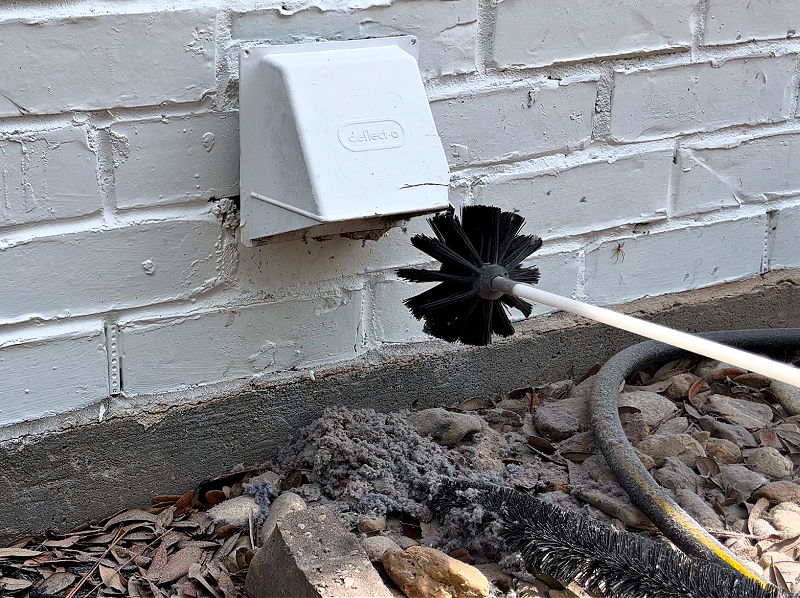 Cleaning out a dryer vent from outside with a dryer vent cleaning kit.