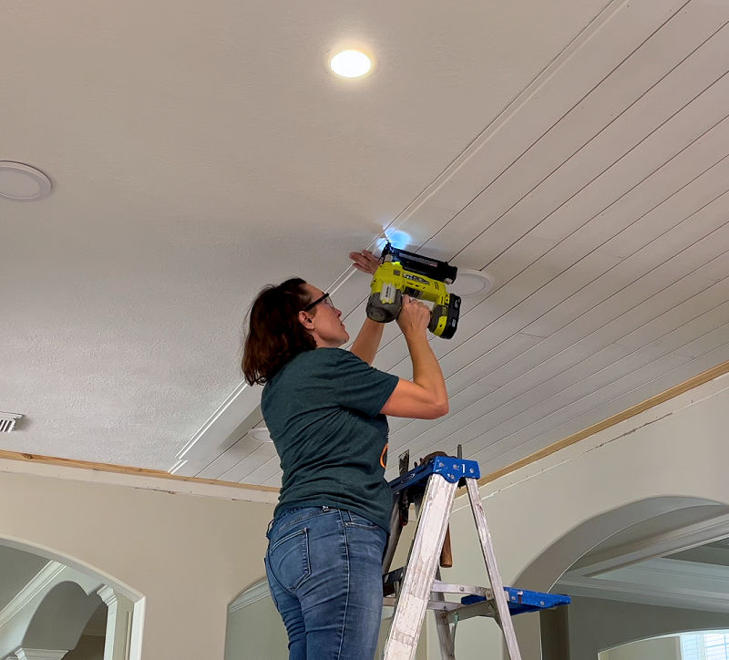 Using a brad nailer to install shiplap on a textured ceiling.