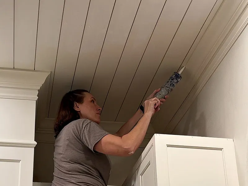 Caulking crown moulding and shiplap before painting.