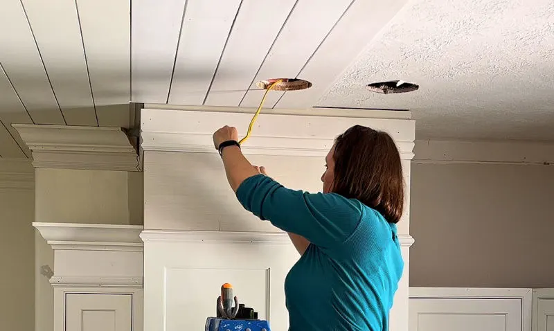 Installing ceiling lights on a shiplap ceiling.