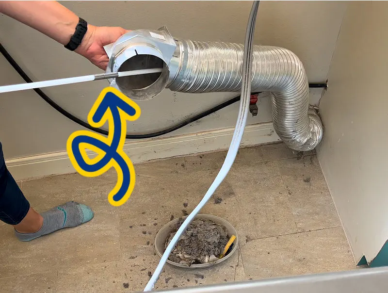 Using a dryer vent cleaning kit inside a dryer duct pipe.