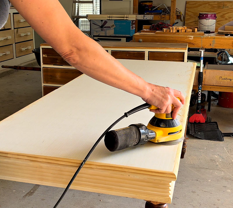 Sanding wood filler on a plywood table top.