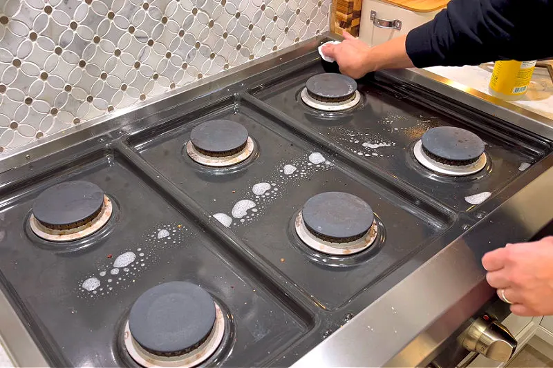 Cleaning a gas stove top.