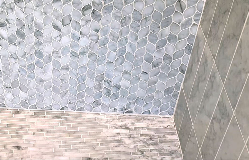 A close up of a clean marble shower floor with white grout.